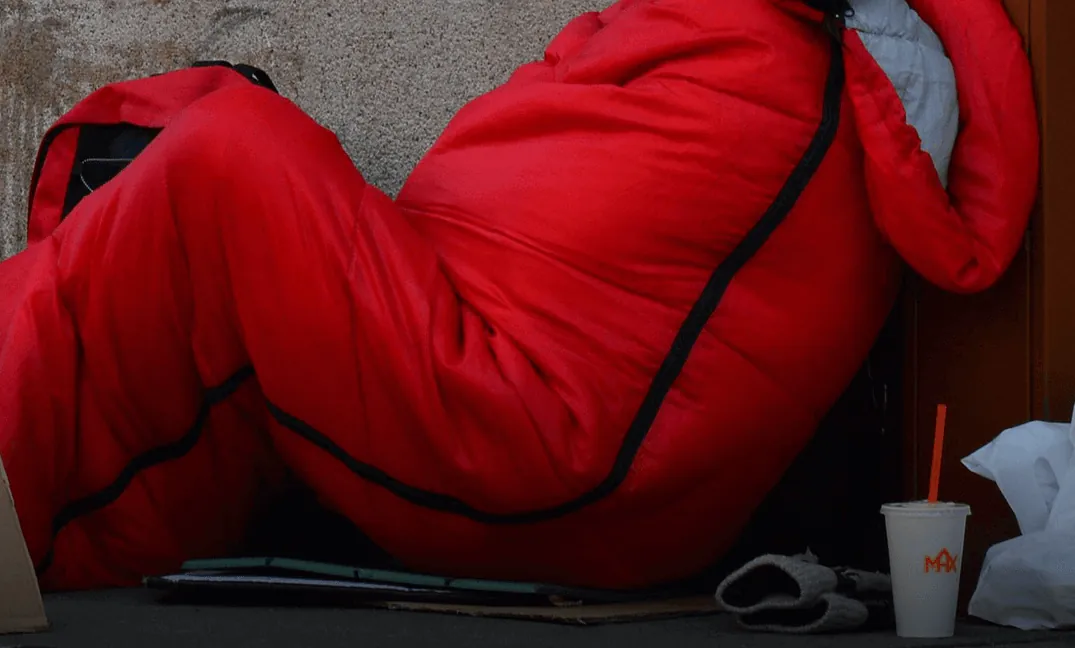 A red sleeping bag against a stone wall